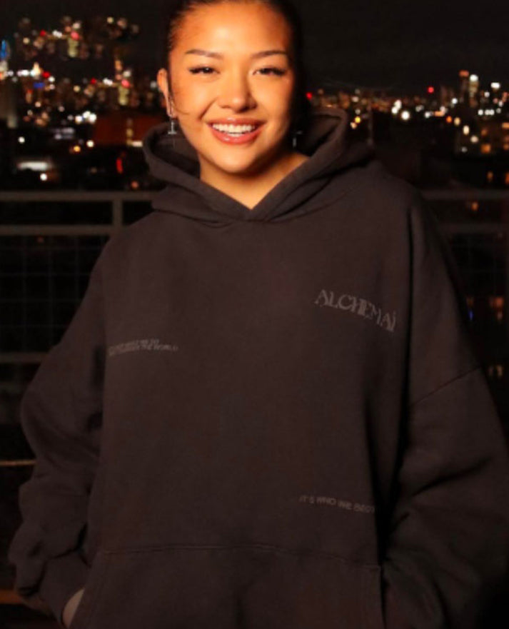 Front view of dark Alchemai hoodie with oversized fit, hood, pouch pocket and subtle Alchemai graphics